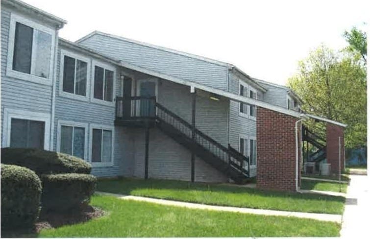 Two-story Pineview apartment buildings with light siding, exterior stairs, and a green lawn