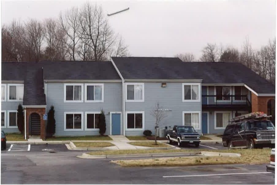 A row of two-story Pineview apartment homes with light-blue siding and white trim seen from the parking area